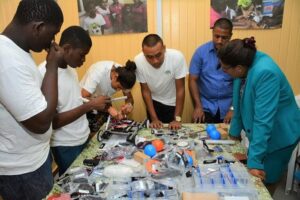 The STEM Guyana team giving Minister of Public Telecommunications, Ms. Catherine Hughes (first, right) a demo of their project