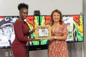 Jennifer DaSilva, wife of the late Roland DaSilva receiving a plaque with an image of the stamp