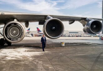 Captain Michael Paheco stands beneath the wing of a Boeing 747-400 beside the engine pod that had earlier exploded during takeoff from Los Angeles. The engine had been secured for transport to Singapore.